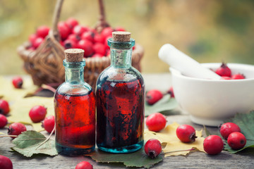 Wall Mural - mortar of hawthorn berries, two tincture or infusion bottles and basket of thorn apples on wooden bo