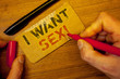 Writing note showing I Want Sex Motivational Call. Business photo showcasing To desire sexual intercourse ExcitementMan creating on yellow paper Hand holding red black pens wooden table