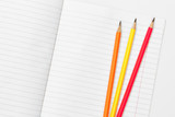 Fototapeta Tęcza - Blank notebook and pencils on white background. School supplies. White sketch book with colourful pencils. Note book and pencil