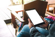 © Farknot Architect - Mockup image of a woman holding black tablet with blank white desktop screen while sitting on wooden chair