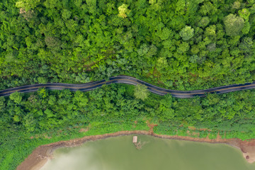 Wall Mural - aerial above view green mountain forest and river in the rain season and curved road on the hill connecting countryside