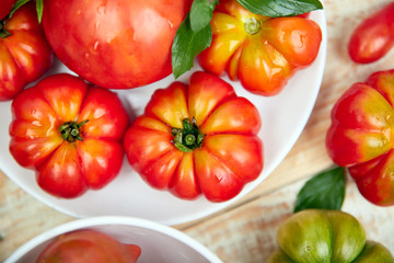 Mix of tomatoes background. Beautiful juicy organic red tomatoes on white wooden table background. Clean eating concept. Copy space, flat lay..