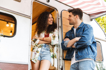 Sticker - Cheerful young couple talking while standing at the campvan