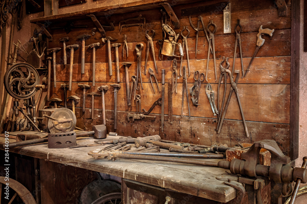 Complete workbench with a wall of tools in a workshop. Vintage look - obrazy, fototapety, plakaty 