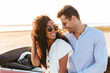Photo of beautiful multiethnic couple hugging and smiling together while standing by car outdoors