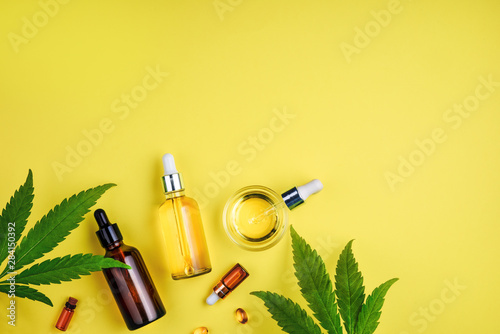 Fotografía Bottles with CBD oil, a dropper, and leaf cannabis on a yellow background