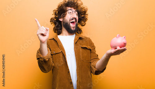 Cuadros en Lienzo young man with crazy hair in motion and a piggy bank