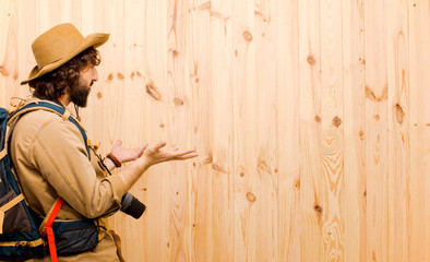 young crazy explorer with straw hat and backpack on wood backgro