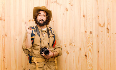 young crazy explorer with straw hat and backpack on wood backgro