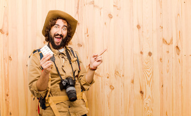 young crazy explorer with straw hat and backpack on wood backgro