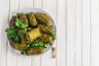 Delicious stuffed grape leaves (traditional doom Mediterranean cuisine Dolma) on a black plate with fresh cilantro and dill