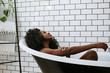 © Leah Flores/Stocksy - Woman Bathing in Tub