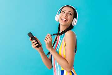 Wall Mural - Image of nice beautiful woman with pigtails looking aside while using headphones and cellphone