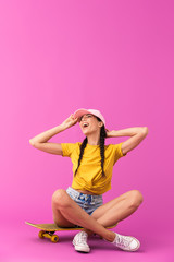 Poster - Image of happy caucasian woman wearing cap laughing and sitting on skateboard