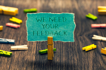 Poster - Conceptual hand writing showing We Need Your Feedback. Business photo showcasing Give us your review thoughts comments what to improve Paperclip retain blue cardboard blurry woody desk paper clip