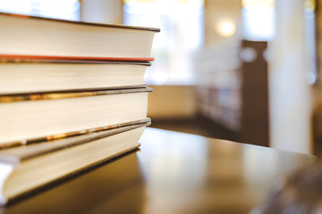 Book in library with old open textbook, stack piles of literature text archive on reading desk, and aisle of bookshelves in school study class room background for academic education learning concept