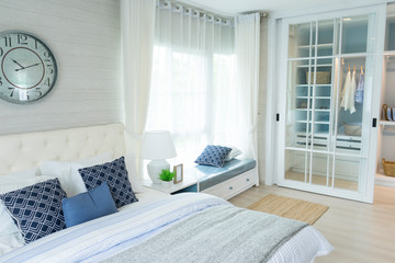 beach blue pillow on bed with side table lamp and large clock on wall in bedroom