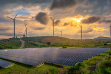 Solar Panels And Wind Turbines Generating Electricity In Power Station Green Energy Renewable With Sunset  Background