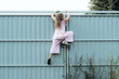 © Nataliya - Girl climbing metal fence outdoor. Curious child on high white painted gates. Naughty kid playing outside, breaking rules. Childhood and youth concept. Restless teen entering private property