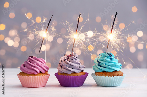 Fotomural Tasty Birthday cupcakes on table against defocused lights