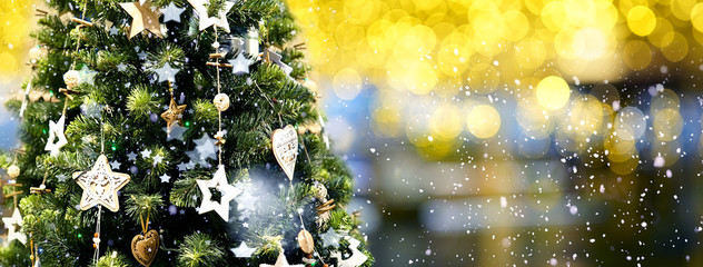 Wall Mural - christmas green tree decorated with wooden garlands of stars on a blurred, sparkling evening dark ba