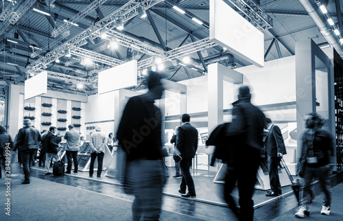 Fotomural business people walking at a trade show booth at a public event exhibition hall,