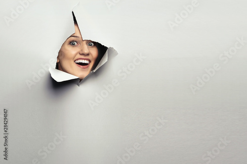 Cuadros en Lienzo Woman looking out from a hole of torn paper