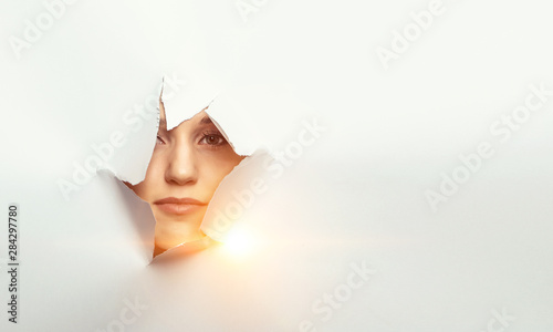 Fotografía Woman looking out from a hole of torn paper