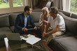 Active senior couple discussing with real estate agent in living room