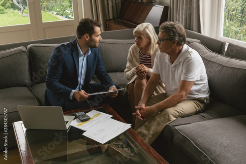 Cuadros en Lienzo Active senior couple discussing with real estate agent in living room