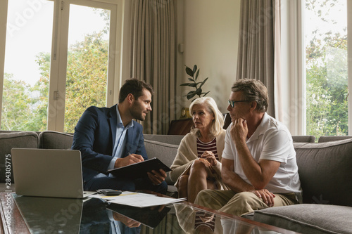 Fotomural Active senior couple discussing with real estate agent over documents in living