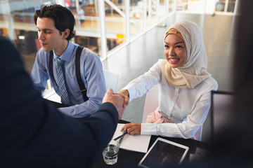 Business people shaking hands with each other while checking in at registration table 