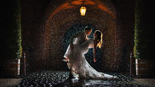 A Bride And Groom Is Dancing Happily In The Rain