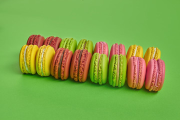 Colored macaron or macaroon, sweet meringue-based confection on green background. Close-up, copy space.