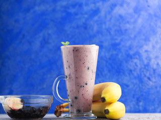 Wall Mural - glass mug of blueberry and banana smoothie on blue background