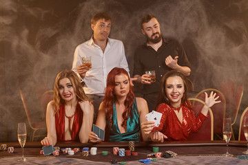 Group of a young wealthy friends are playing poker at a casino.