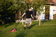 © romul014 - Young man use grass mower in his backyard