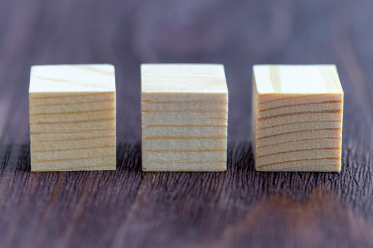three wooden cubes on a Burgundy wooden background, space for your text, blank for design, selective focus, tinted image