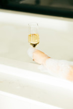 Hand Holding Glass Of Champagne In Bubble Bath