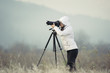 photographer with camera and tripod outdoor taking landscape picture