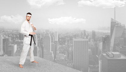 Wall Mural - Young karate trainer doing karate tricks on the top of a metropolitan city