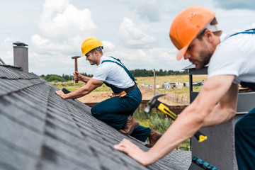 Wall Mural - selective focus of handsome handyman repairing roof with colleague