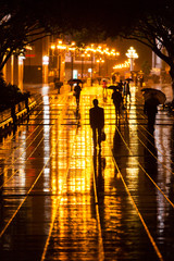 Sticker - China, Chongqing, Pedestrians walking with umbrellas along brightly lit pedestrian street at night on raining autumn evening