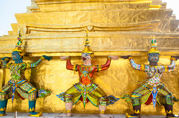 Canvas Print - Bangkok, Thailand - Three statues are standing and holding a heavy, golden building.