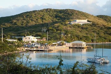 Wall Mural - Vieques, Puerto Rico - A seaside marina is set in the waters of a calm ocean bay. In the foreground a sailboat can be seen anchored in the bay.