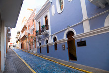 San Juan, Puerto Rico - Two People Are Walking Up A Sloped Brick Lane In An Old World Section Of The City. The Brick Road Is Painted Blue.