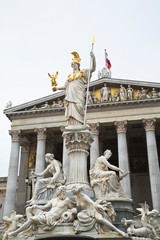 Sticker - Austria, Vienna. A romanesque statue stands on a dry water feature in front of a building with columns.