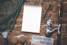 Fisher Book Template Or Fishing Tips. Fishing Gear And A Blank Page Notepad With A Copy Space On Wooden Background.
