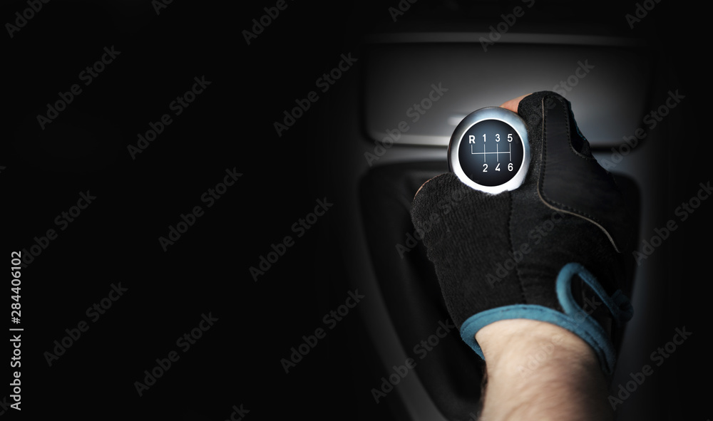 Dłoń w rękawiczce na sześcio biegowej dźwigni zmiany biegów w samochodzie osobowym, tekst. - obrazy, fototapety, plakaty 