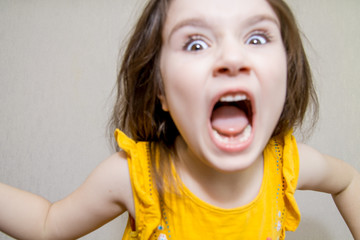 defocused funny close up portrait of a Little agressive angry girl screaming on white background